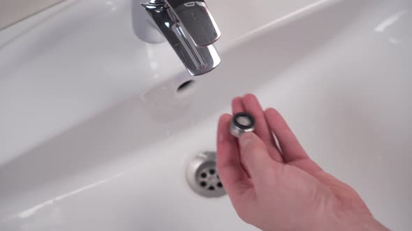 Assembling a filter with a rubber gasket on a shiny public toilet faucet after cleaning