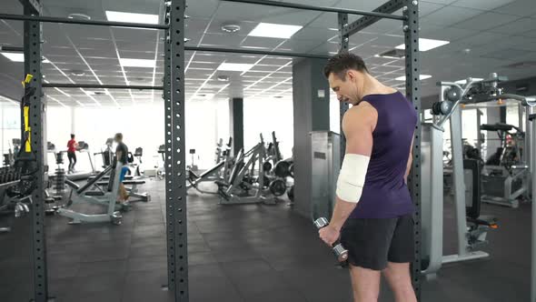 Muscular Man With Injured Elbow Training With Dumbbell Gym, Recovery, Strength
