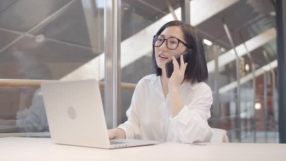 Pretty Asian Woman Having Phone Call on Workplace