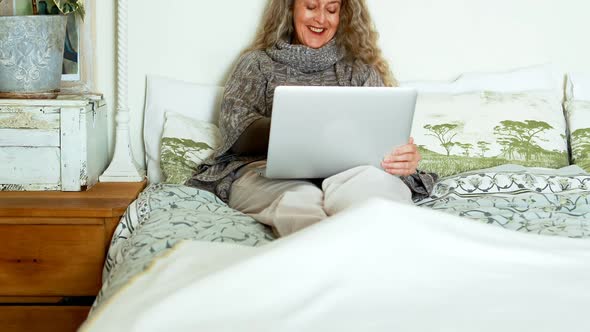 Mature woman using laptop in bedroom 4k