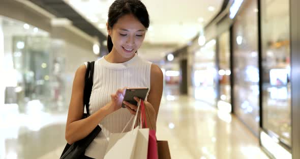 Woman using cellphone and hold paper bag