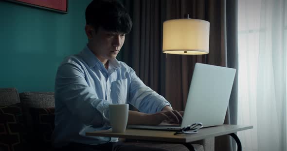 Young Attractive Asian Vietnam Man Busy Work Computer or Smart Tablet on Laptop at Home in Freelance