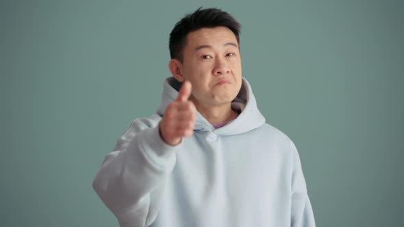 Positive Asian man wearing hoodie showing thumb up gesture