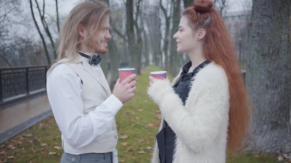 Side View of Young Caucasian Boyfriend and Girlfriend Standing Face To Face in Autumn Park