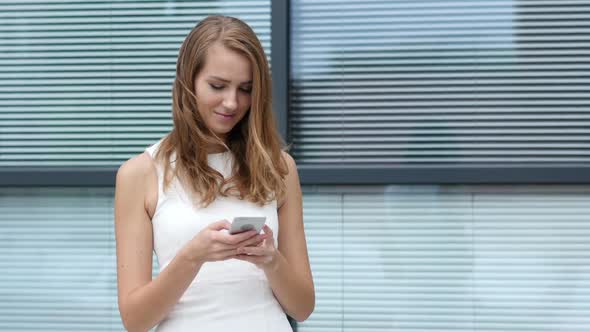 Text Messaging on Smartphone by Beautiful Girl, Outside Office