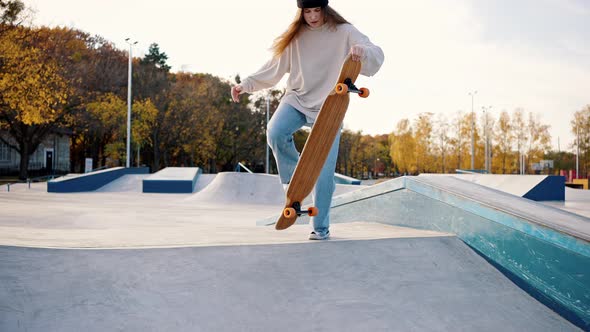 Stylish Casual Dressed Girl Rides Off the Springboard on a Skateboard