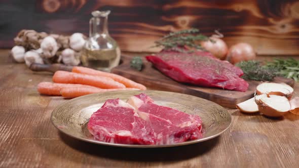 Slow Slide Movement Showing Two Pieces of Raw Meat and Vegetables on a Wooden Background