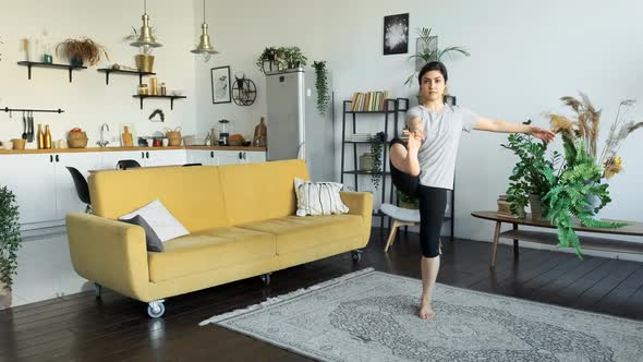 A Young Indian Woman Does Yoga Meditation At Home, Does A Balance Exercise