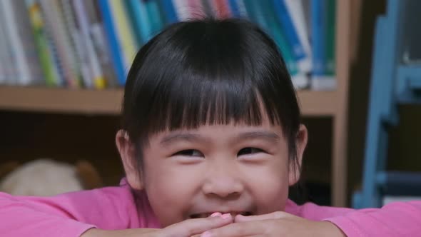 Portrait of a funny little girl smiling and looking at the camera sitting on the sofa at home. Cute