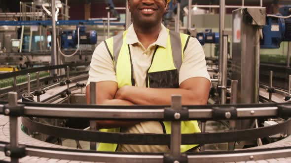 Portrait of worker standing with arms crossed near production line