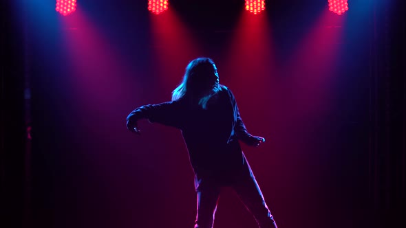 Silhouette of a Talented Young Girl Hip Hop Dancer. Hip Hop Street Dance on a Stage in Dark Studio