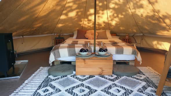 Interior of a glamping tent with chairs outside, nature, green grass and trees, trail