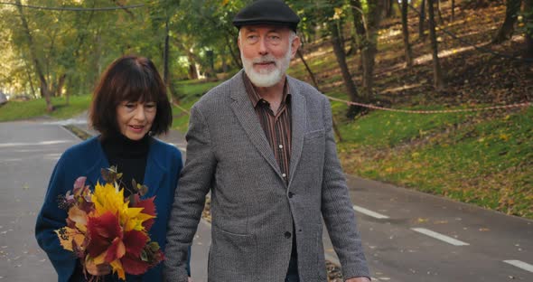 Close-up View of Lovely Smiling Senior Citizens of Wife with Bouquet of Leaves and Husband Dressed