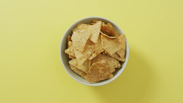 Close up of nachos in a bowl with copy space on yellow surface