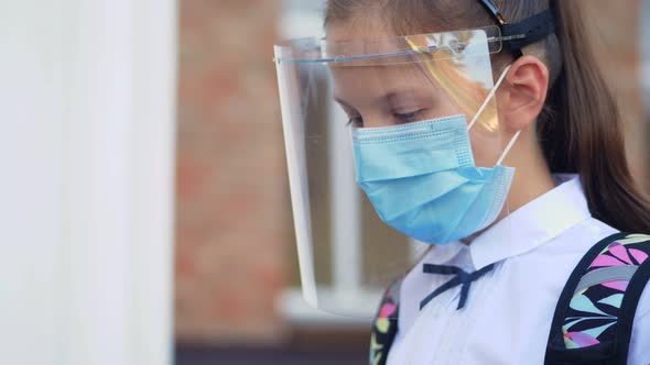 Close-up. Schoolgirl, Teenage Girl, in Medical Mask and Protective Face Shield, Is Using Laptop