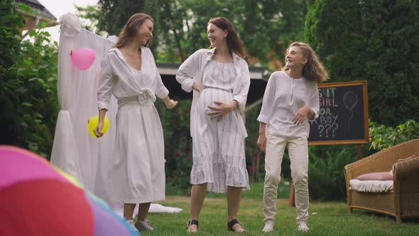 Excited Pregnant Woman and Friends Dancing in Slow Motion on Backyard Celebrating Baby Shower Party