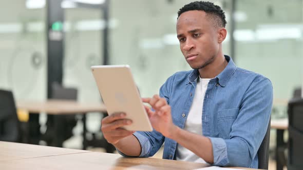 Pensive Casual African Man Using Tablet in Office 