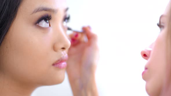 Attractive Asian Young Woman Raising Brown Eyes Up During Working Professional Makeup Artist Closeup