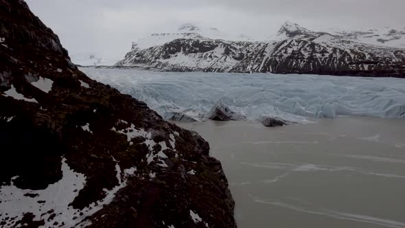 Aerial view of glacier and lake with iceberg floating on the water