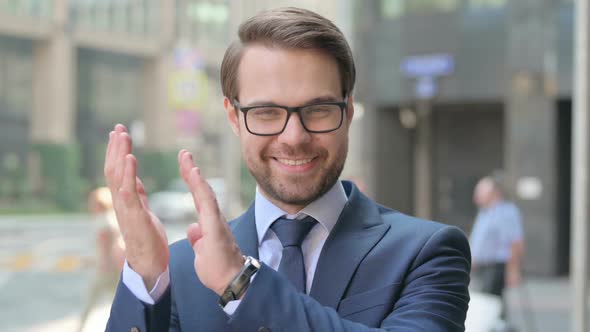 Portrait of Businessman Clapping while Standing Outside