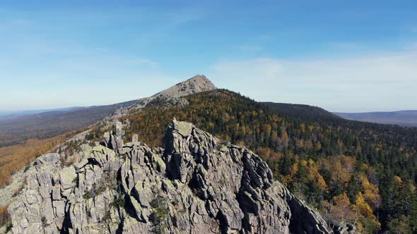 Aerial view of the mountains with rocks and beautiful autumn woods on the slopes