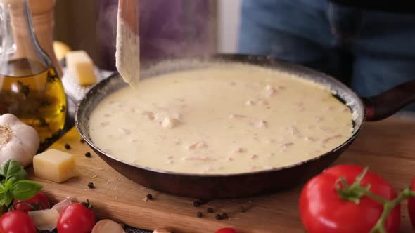 Making Pasta Carbonara  Mixing Sauce Made of Cream and Chopped Pancetta Bacon in Frying Pan