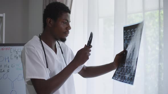 Side View Concentrated African American Radiologist Examining Brains Xray with Magnifying Glass