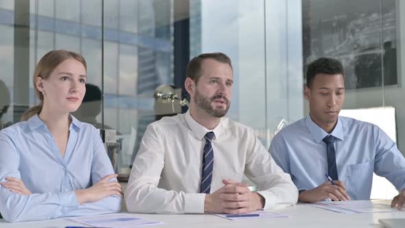 Middle Aged Businessman Giving Presentation with Assistants on Office Table 