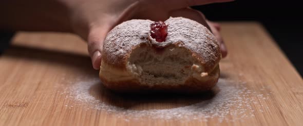 Person picking up a hanukah jelly doughnut and returning it partially eaten