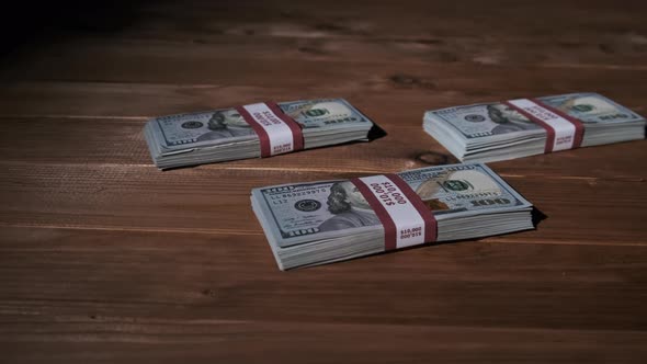 Three Stacks of 10000 American Dollars Banknotes in Bundles Lie on Wooden Table