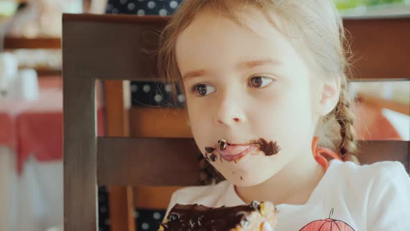 Happy Childhood Cool Girl Eating Chocolate Cake in a Cafe on the Street the Whole Face is Covered