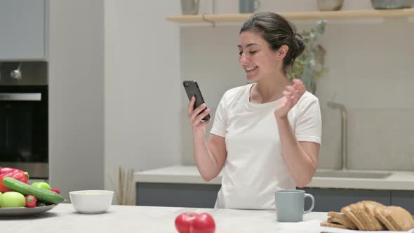 Young Indian Woman Doing Video Call on Smartphone in Kitchen