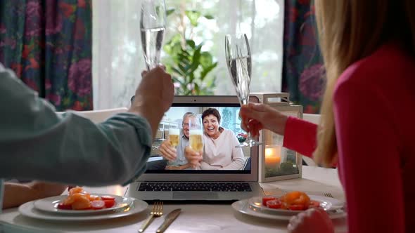 A Young Couple and an Elderly Couple Celebrate Together Using Laptop Video Call.