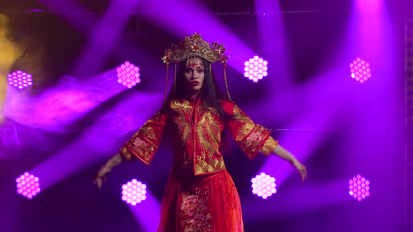 Attractive Brunette Dancing in a Dark Studio with Smoke and Purple Neon Lights. Young Woman in Red