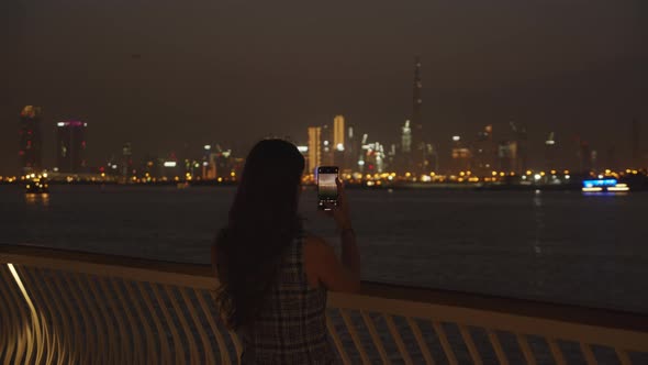 Woman Taking Pictures of Dubai Skyscrapers at Night