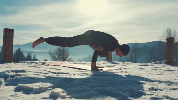 Caucasian Senior Man Doing Yoga Exercises in Front of Amazing Sunset on the Winter Mountains