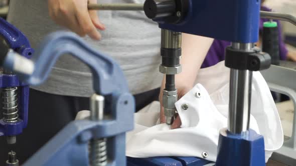 Closeup View of Hands of Sewer Attaching Metal Round Snaps to Clothes with Help of Special Machine