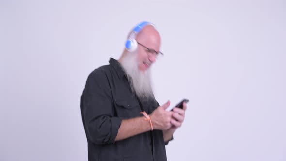 Mature Bald Bearded Man Listening To Music While Using Phone