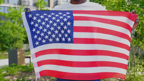 Close Up Afroamerican Man Holding American Flag on Background Trees in Summer