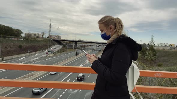 Woman with mobile crossing the overpass
