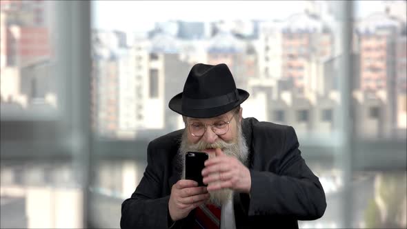 Expressive Cheerful Longbearded Old Man Taking Picture Using His Phone