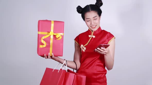 woman wear cheongsam and using mobile phone with shopping bag and gift box