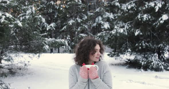 Cute Curly Girl Drinks Warm Tea In The Winter Snowy Forest