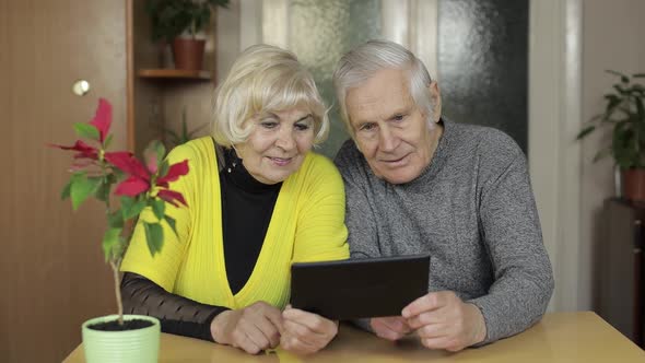 Pretty Mature Senior Couple Grandparents Making Video Call with Tablet at Home