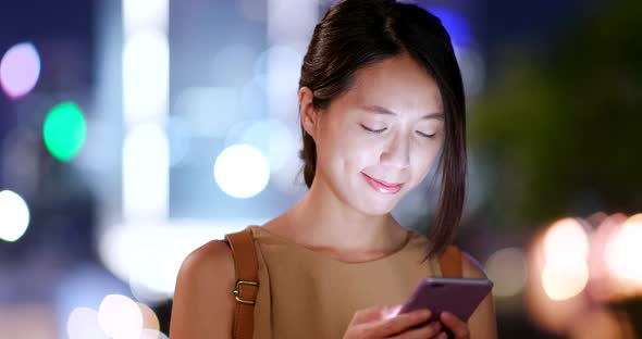 Woman look at mobile phone in city at night