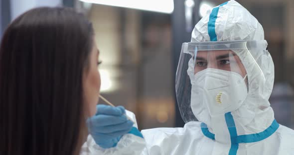 Male Doctor Wear Chemical Protection Takes a PCR Swab From a Woman Test for the Presence of