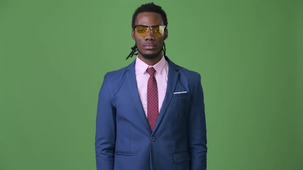 Young Handsome African Businessman with Dreadlocks Against Green Background