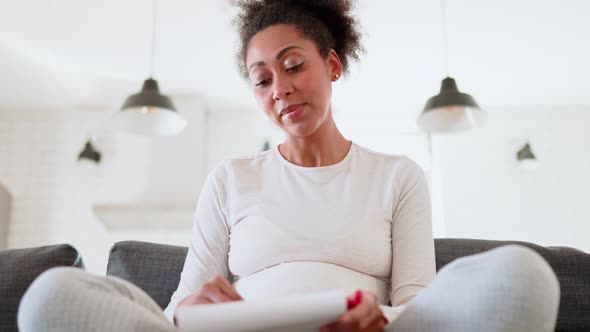 Young African pregnant woman drawing