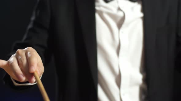 Close Up Of Conductor's Hands Holding A Baton And Moving In The Black Studio