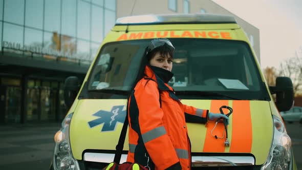 Proud Female Paramedic Posing at Ambulance Vehicle Near Hospital